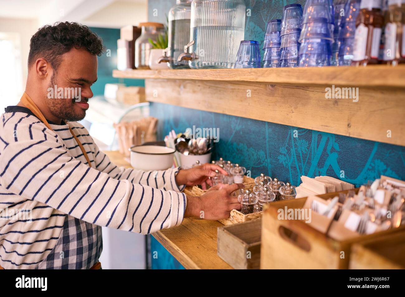 Man With Down Syndrome Working In Coffee Shop Or Restaurant Stock Photo