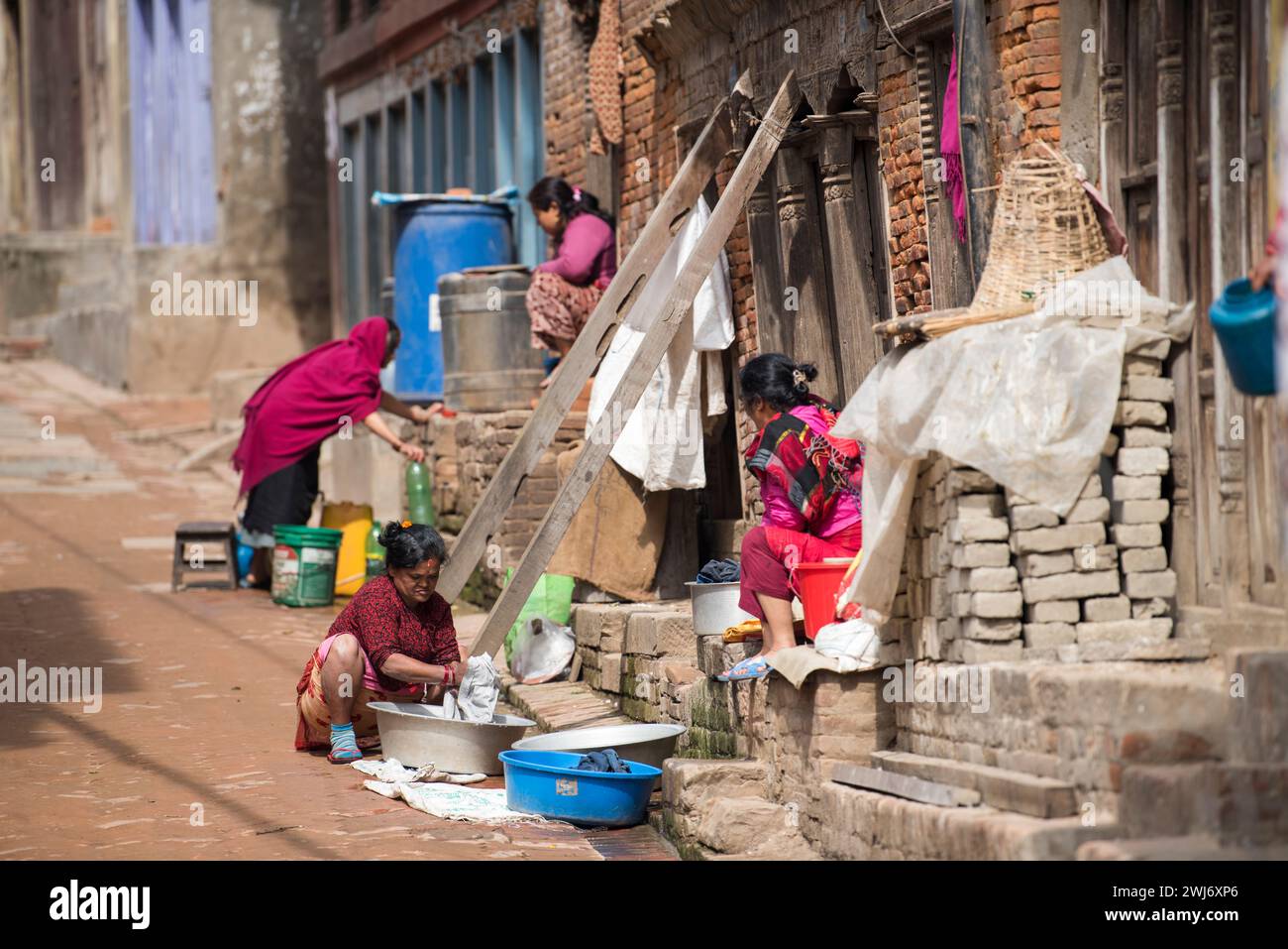Kathmandu, Nepal- April 20,2023 : Women wash clothes and dishes on the streets of Patan Durbar Square. Stock Photo