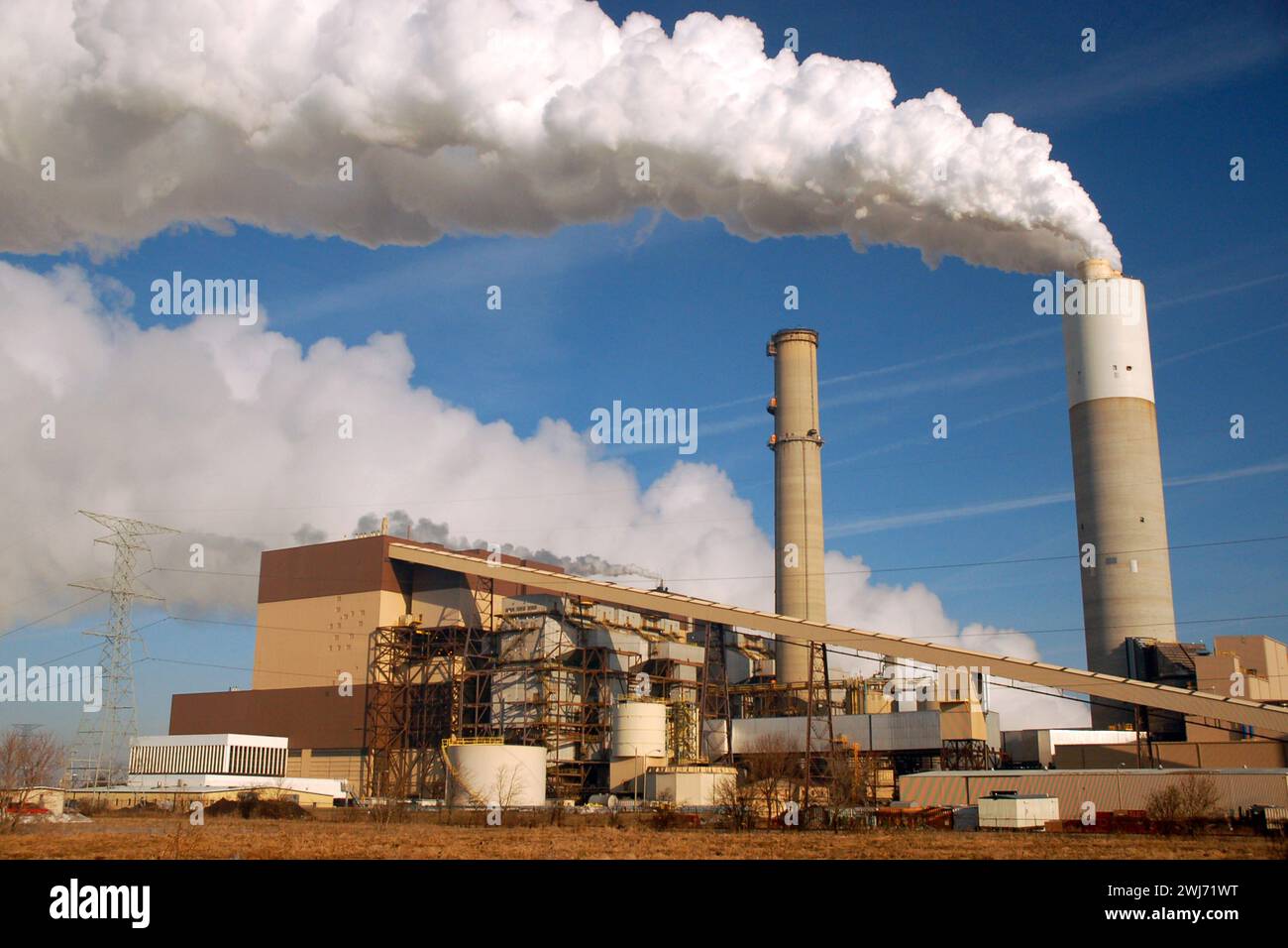 A smoke stack from a factory spews smoke and carbon pollution into the air Stock Photo