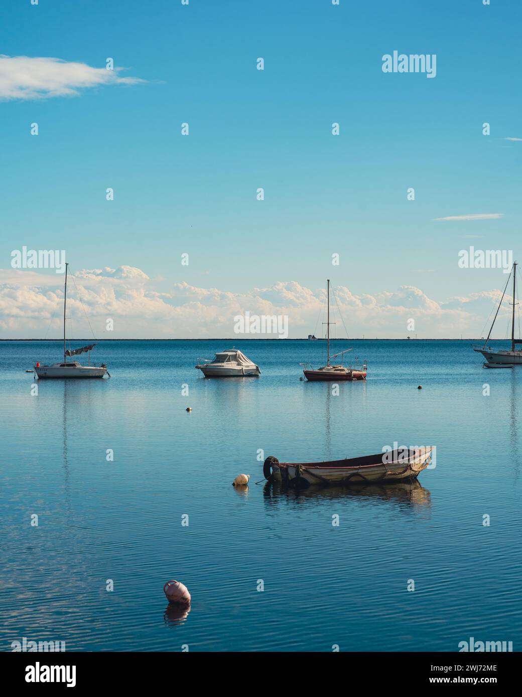 Sailboats and buoys peacefully docked in serene lake waters Stock Photo