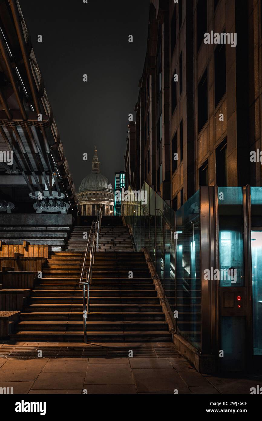St Pauls from Thames Pathway under Millennium Bridge, London, 2020. The steps lead upwards and the dome is centred against a clear cold night sky. Stock Photo