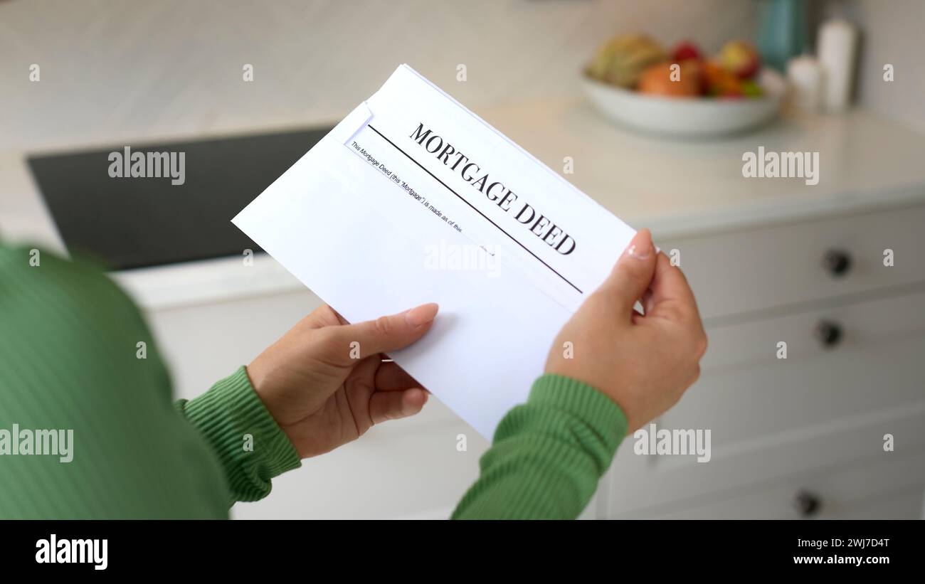 Close Up Of Woman Opening Letter Containing House Mortgage Deed Stock Photo