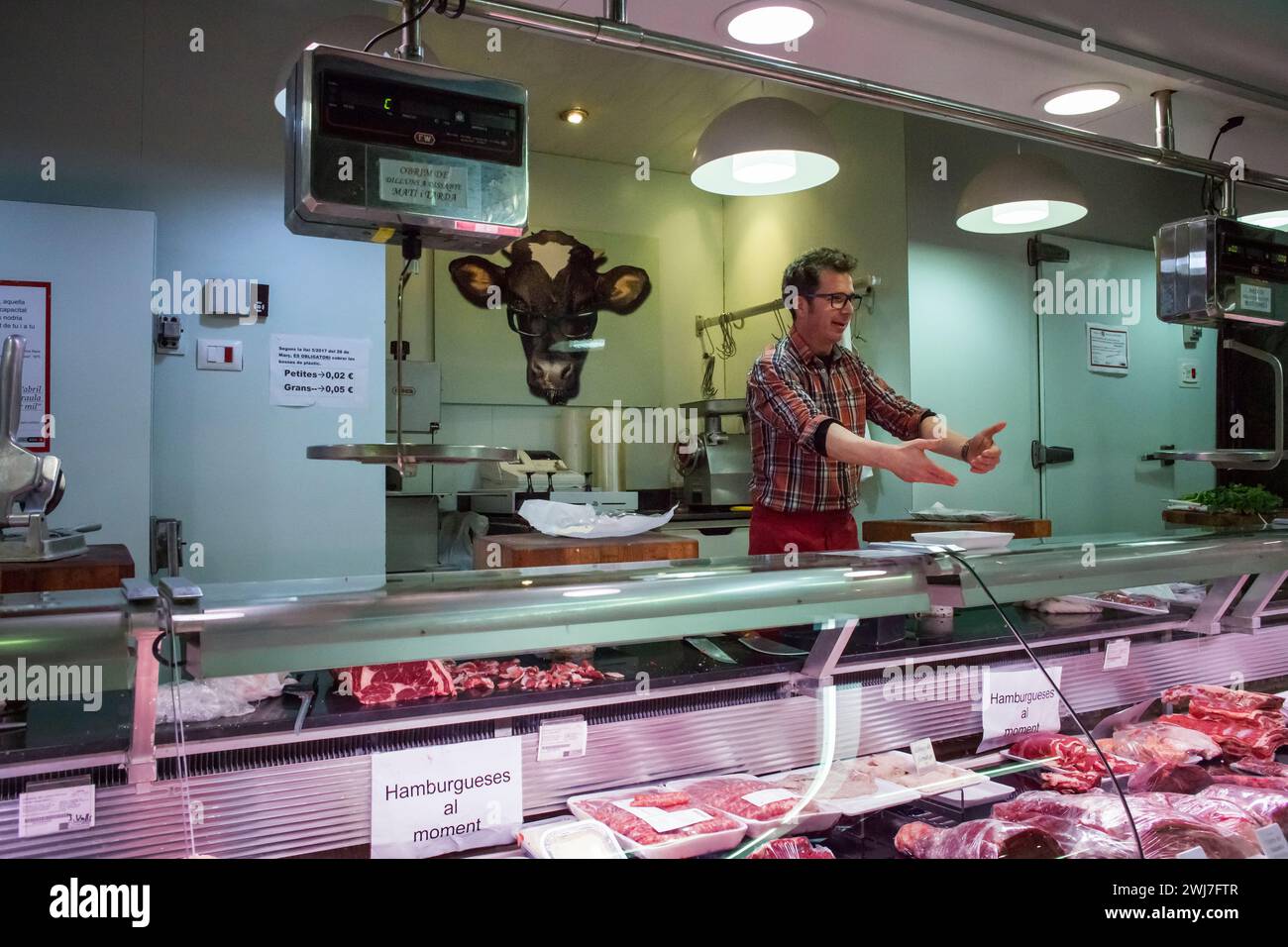 Butcher in his butcher’s stall in the old Abaceria Central Market of Barcelona Stock Photo