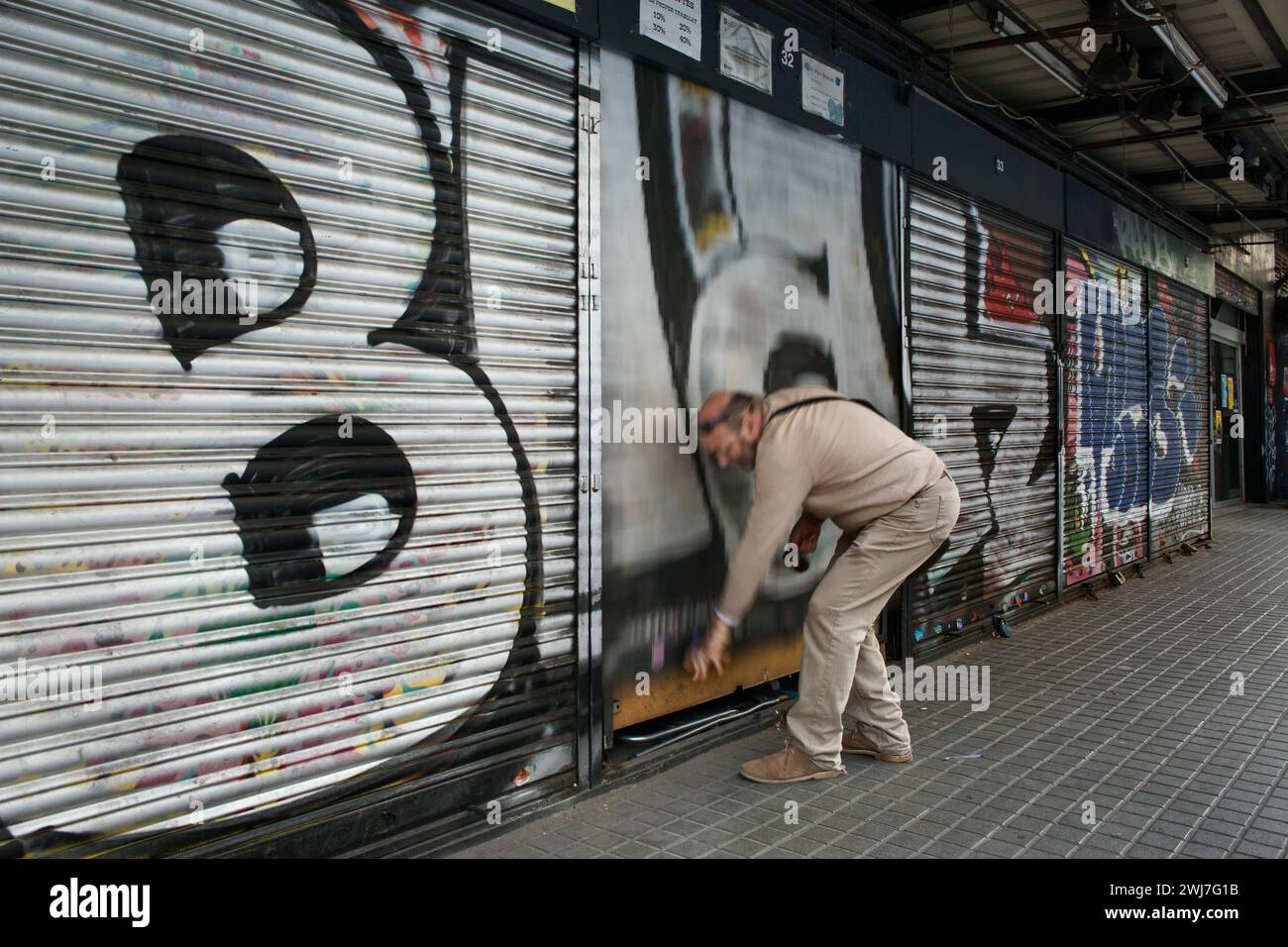 Man closing the shutters of his exterior stall in the old Abaceria Central Market Stock Photo