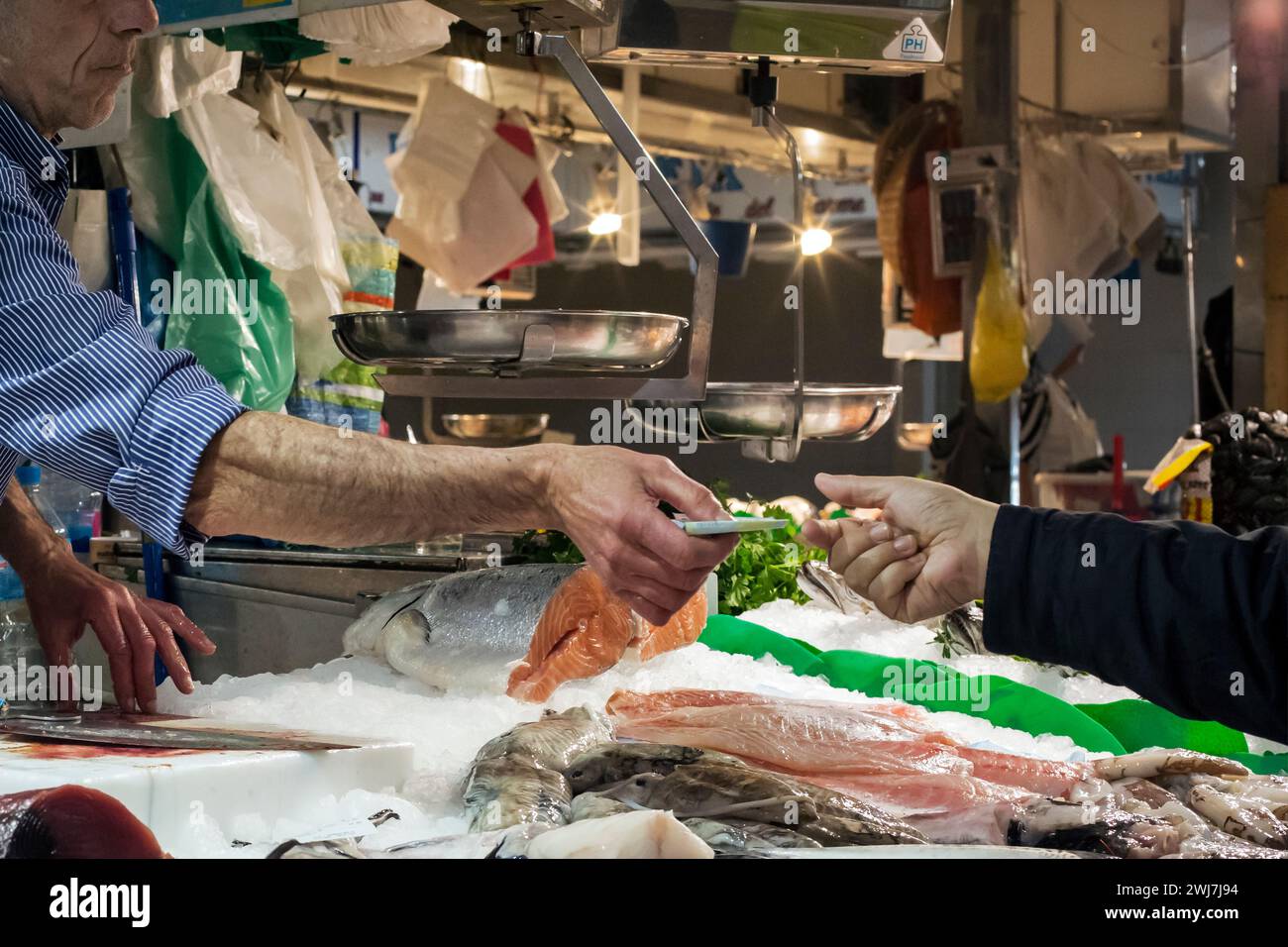 Fishmonger giving the change to a customer of the old Abaceria Central Market in Barcelona Stock Photo