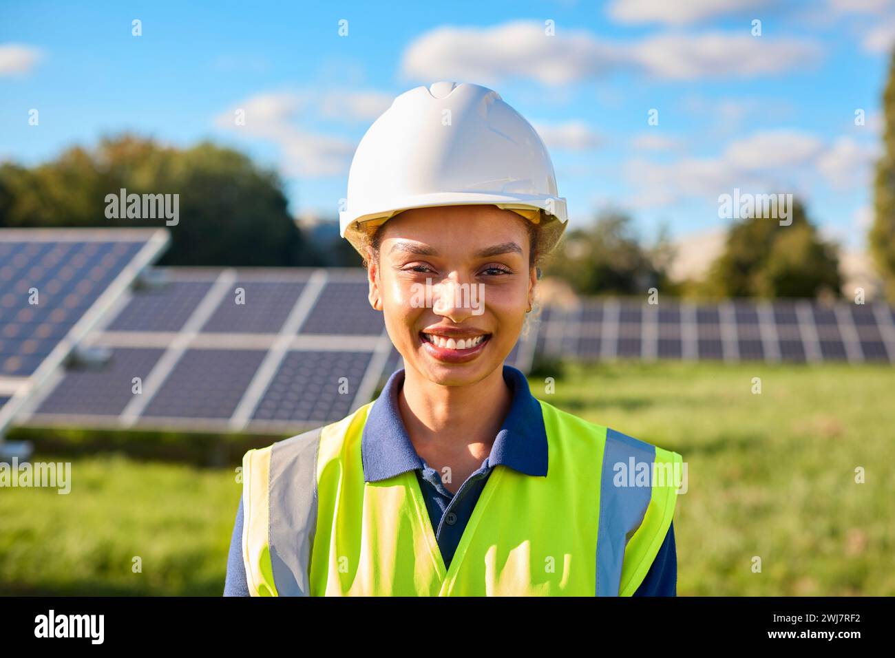 Portrait Of Female Engineer Inspecting Solar Panels In Field Generating Renewable Energy Stock Photo