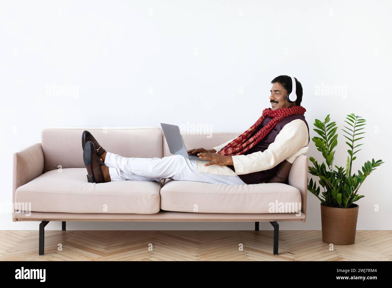 Relaxed mature indian man using laptop and headset Stock Photo