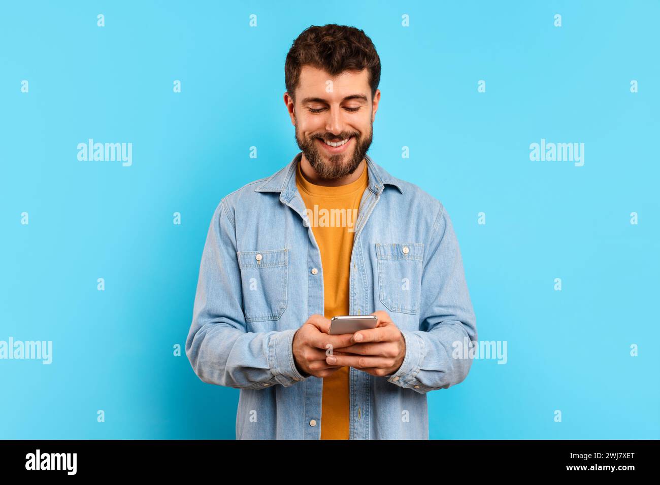 Happy young man browsing an app on his smartphone, studio Stock Photo