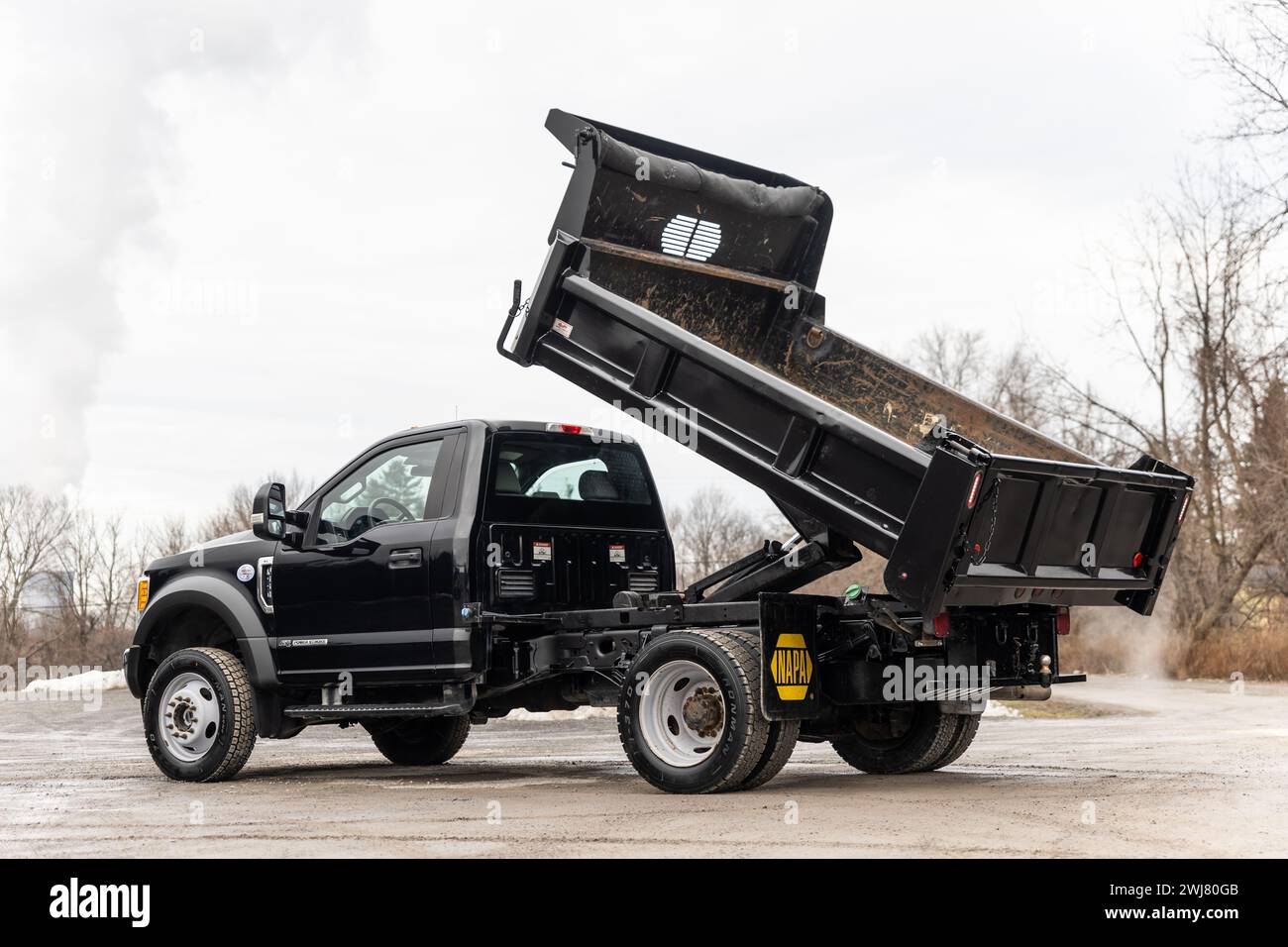 Black pickup truck with dump truck bed and attached trailer Stock Photo