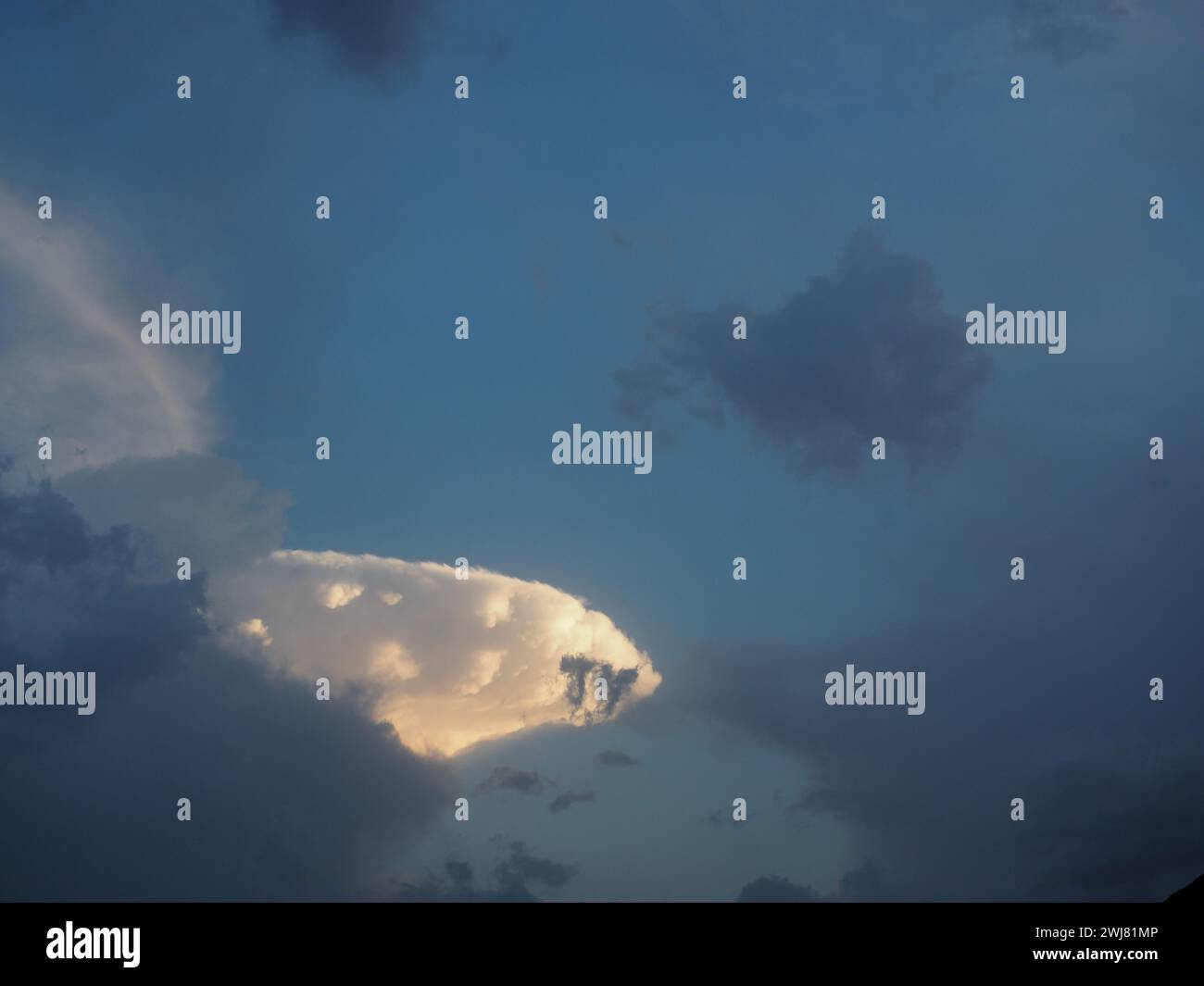 Sun shining through clouds over beach with red umbrella Stock Photo