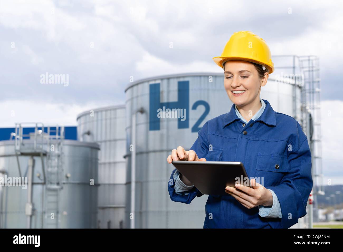 Female engineer with tablet computer on a background of Hydrogen factory. Stock Photo