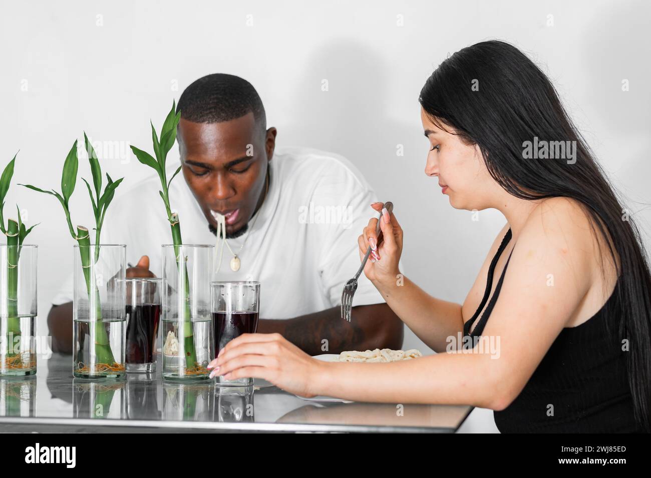 young latin couple, eating in the dining room with a lot of seriousness. multicultural couple. Stock Photo
