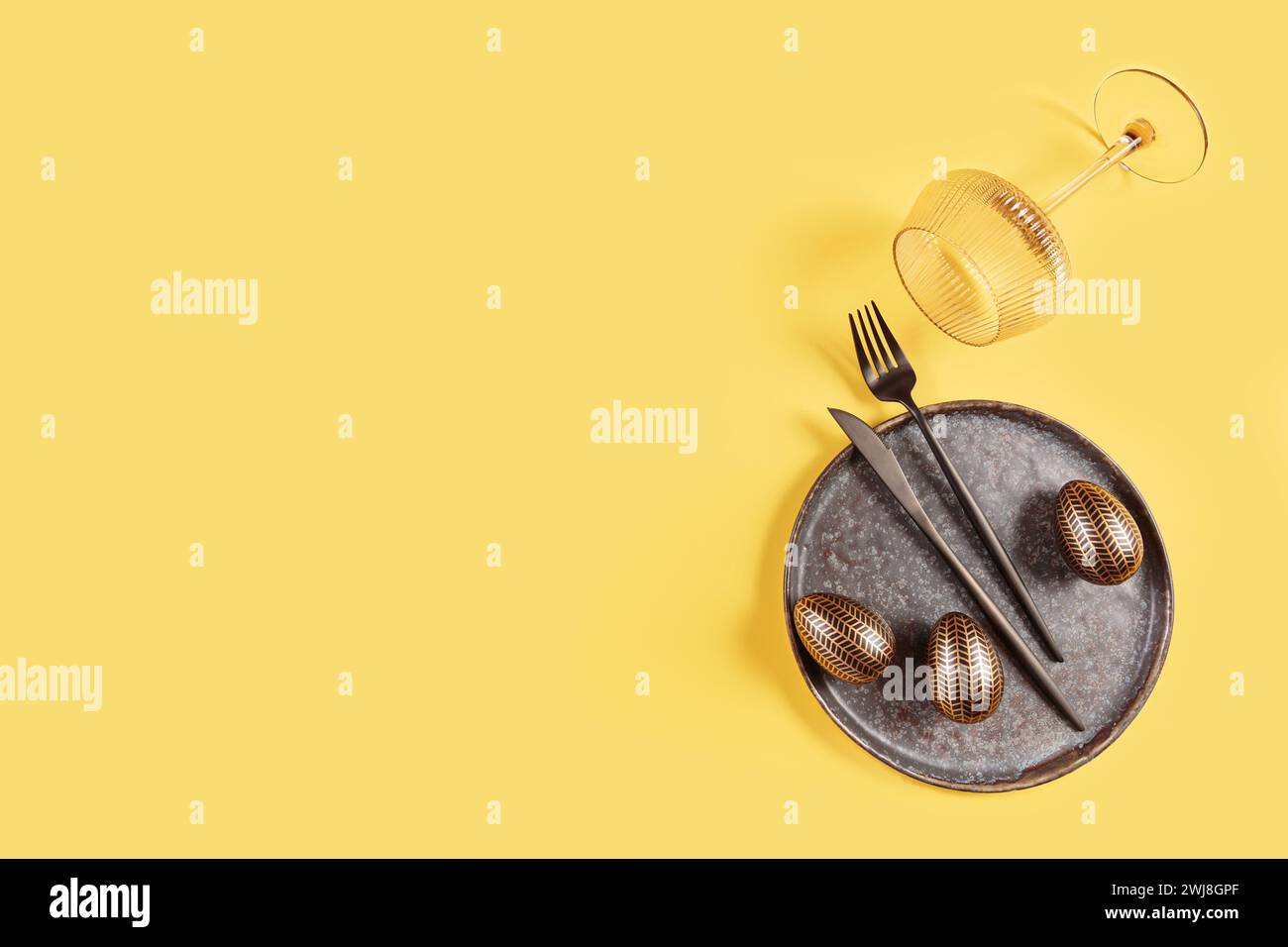 Table place setting and festive easter decor on yellow background Stock Photo