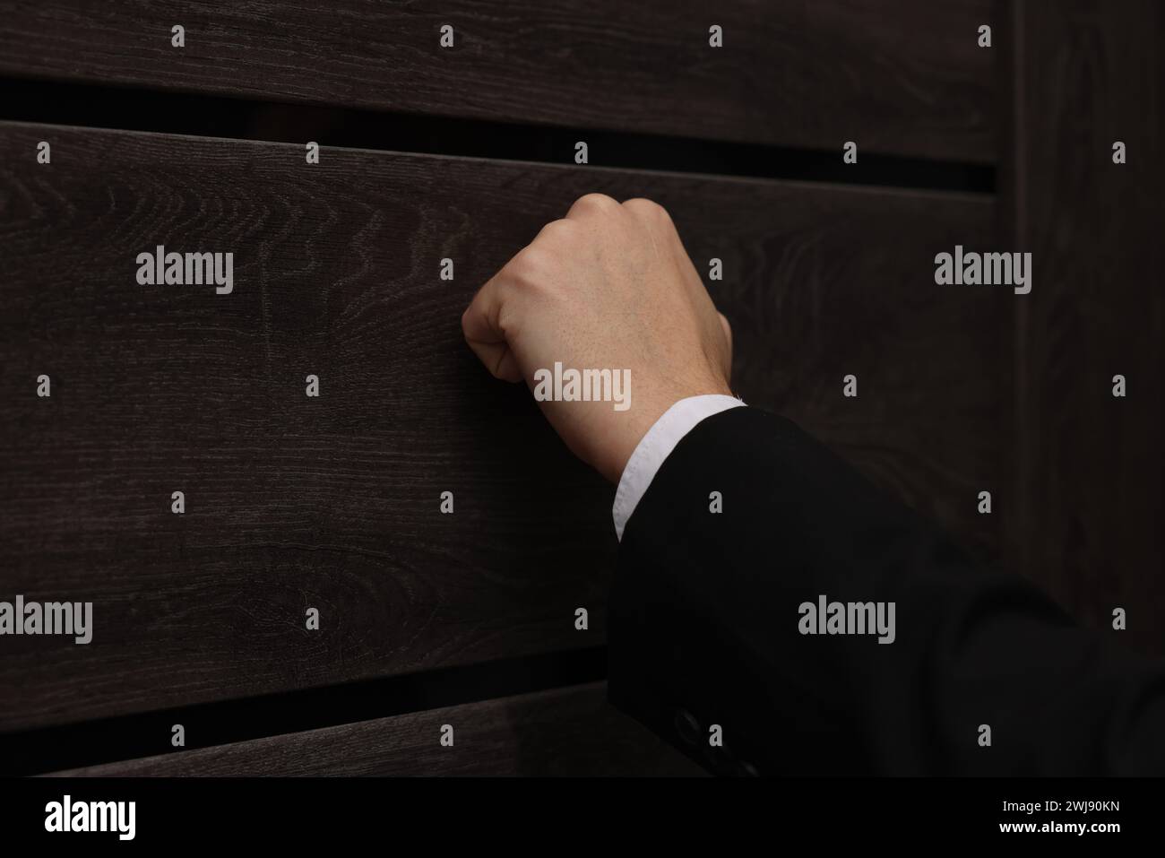 Collector knocking on door indoors, closeup view Stock Photo