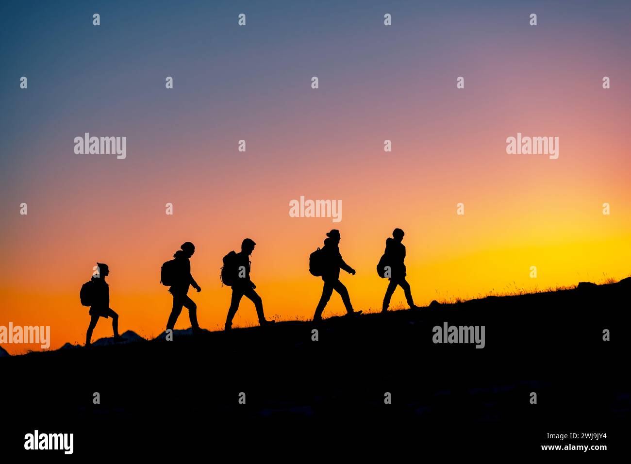 Group of hikers with backpacks silhouettes walks uphill in mountains ...