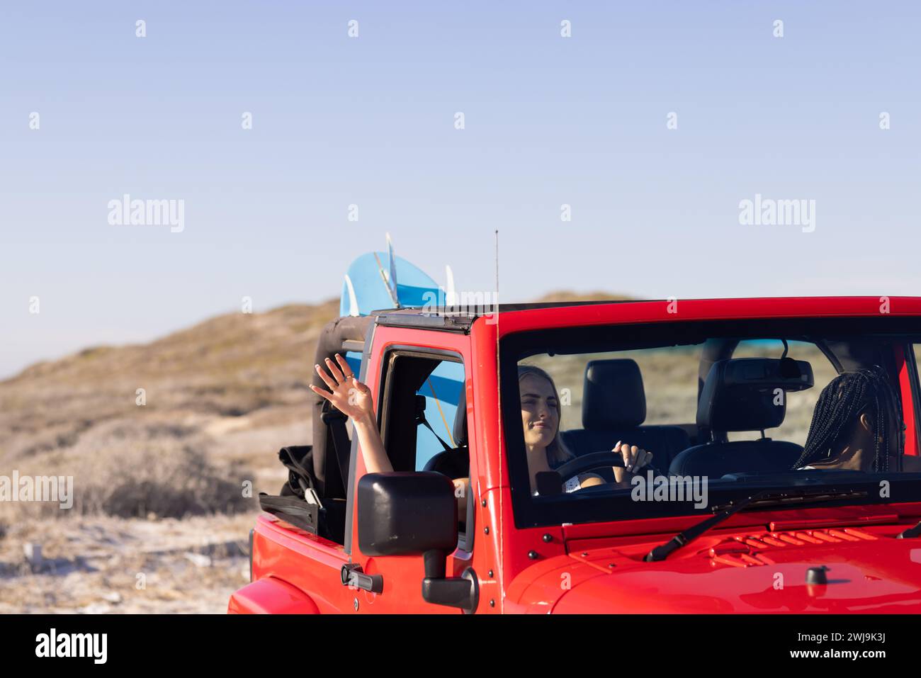 Young African American woman and young Caucasian woman enjoy a sunny beach drive on a road trip Stock Photo