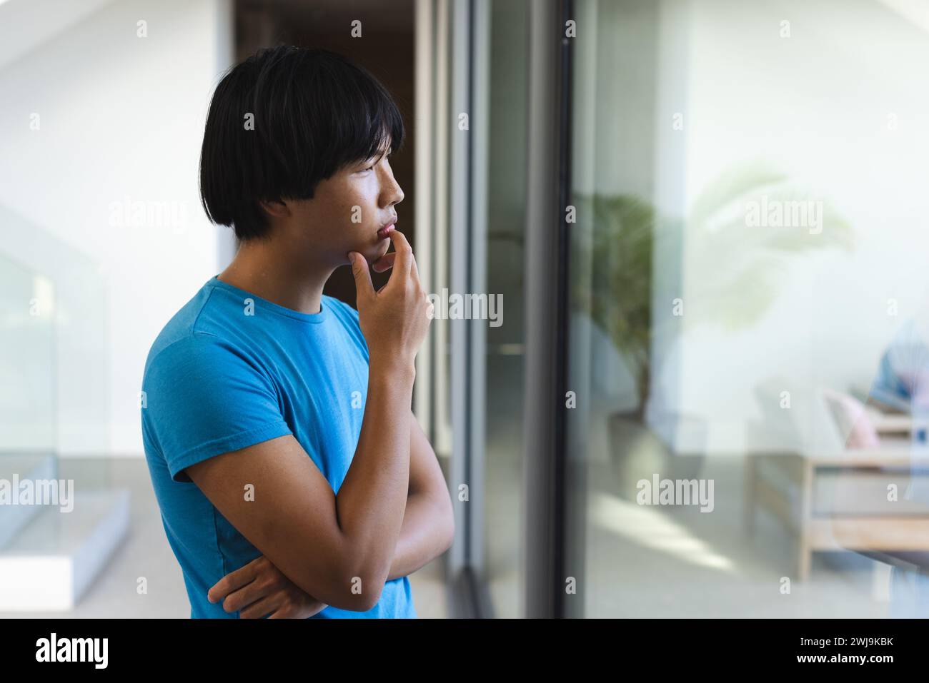 A sad teenage Asian boy looks thoughtful, with copy space Stock Photo