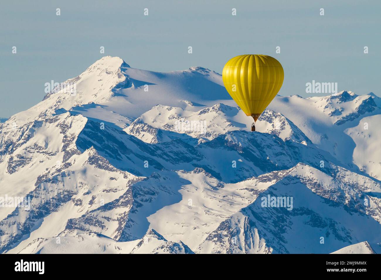 A yellow balloon flying over snow-covered mountains Stock Photo
