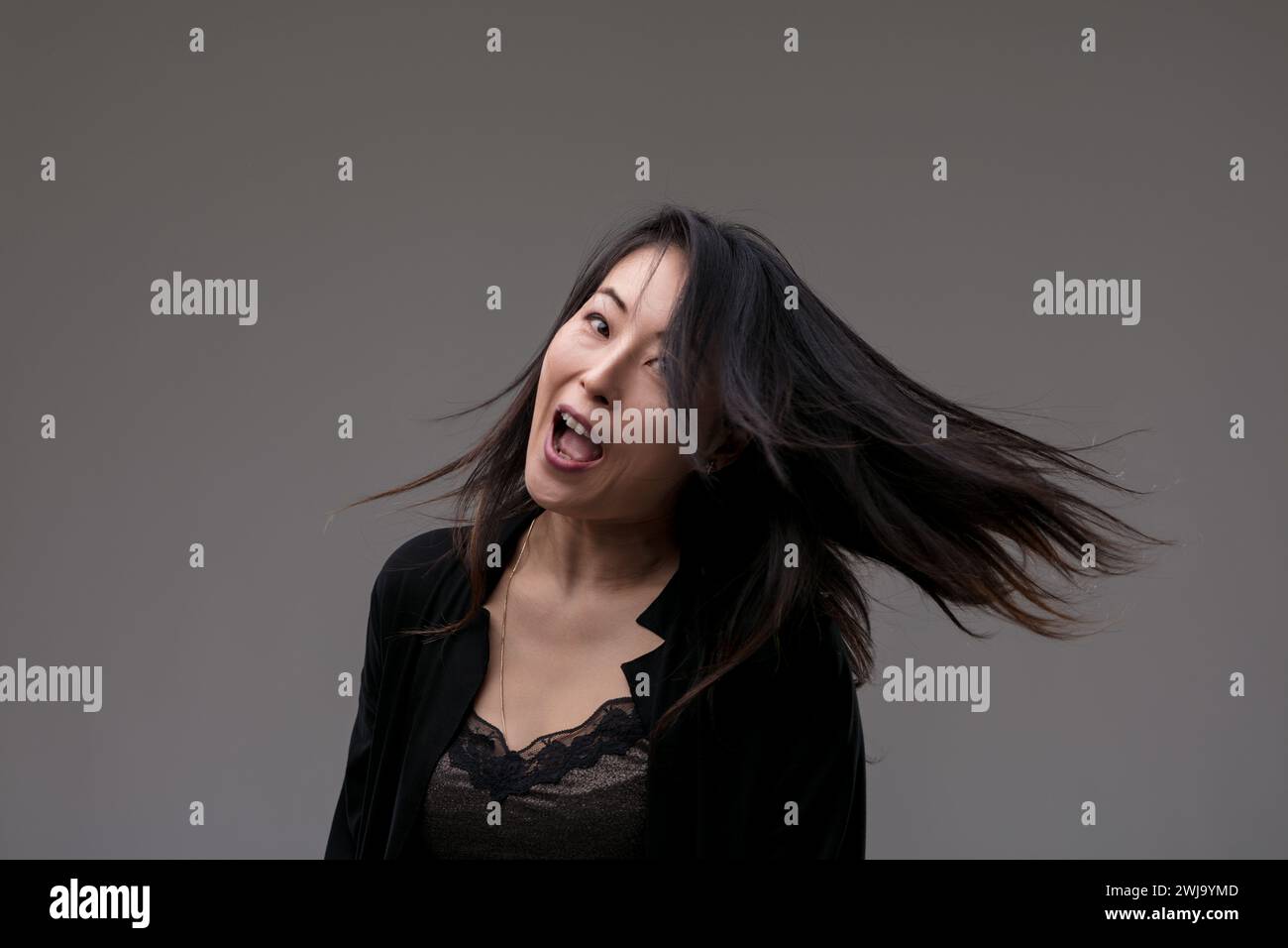 Her laughter rings out, hair tousled by joy, capturing a spontaneous burst of delight Stock Photo