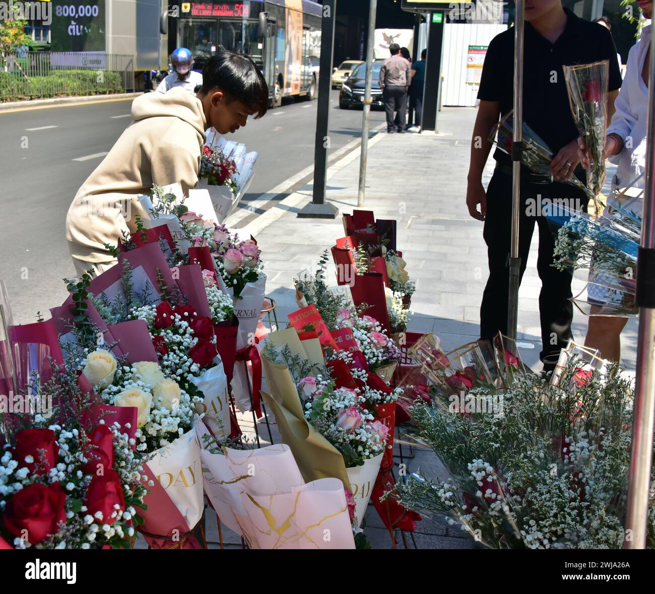 A young man (left) sells flowers on valentine's day on Silom Road, Bangkok, Thailand, South East Asia Stock Photo