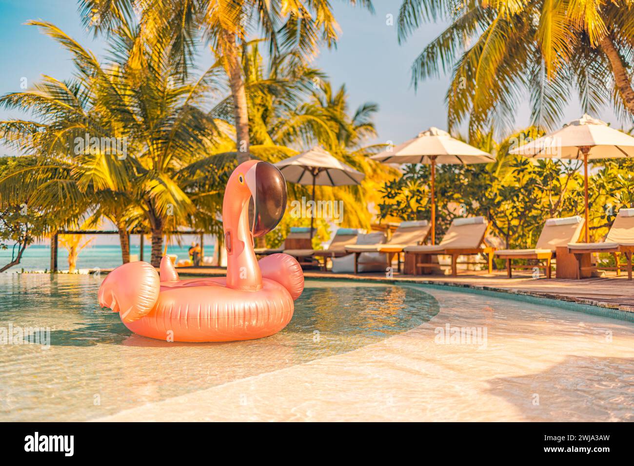 Summer tourism swimming pool inflatable pink flamingo, luxury resort hotel poolside. Happy sunset tropical paradise island infinity pool sea view Stock Photo