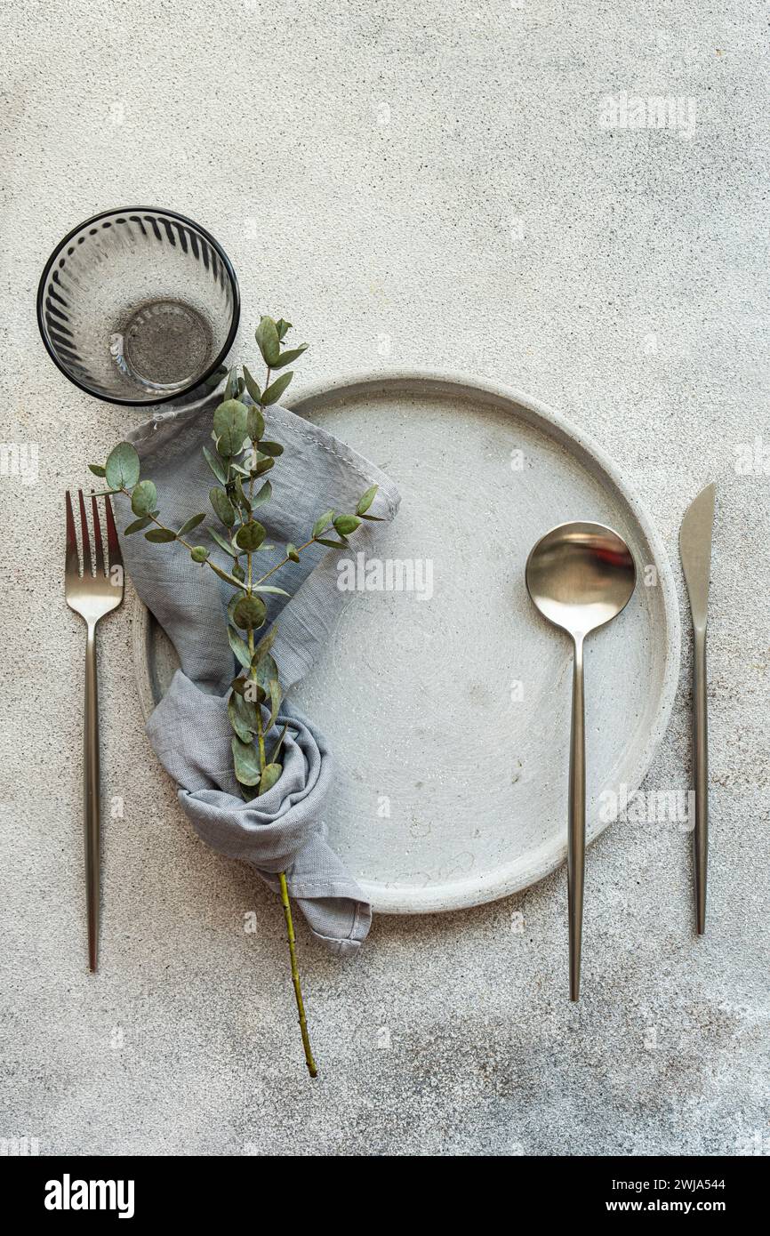 An elegant table setting featuring a white plate, silverware, and natural greenery for a sophisticated dining experience Stock Photo