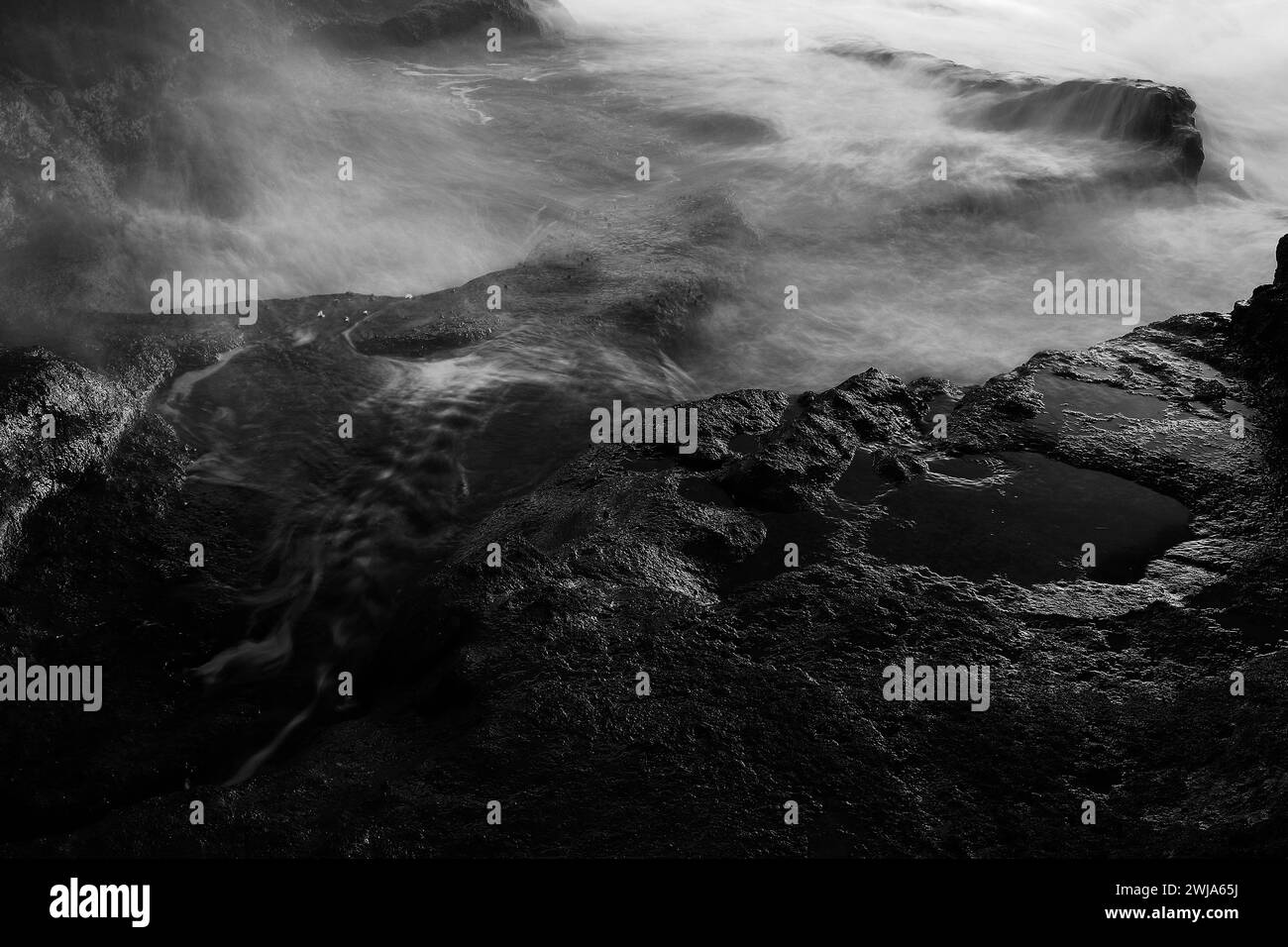 Ethereal black and white seascape with water swirling around rock formations Stock Photo