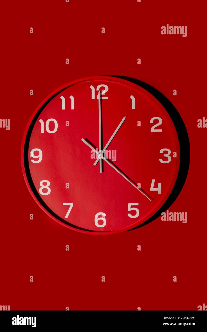 A modern red wall clock showcases a simplistic design against a