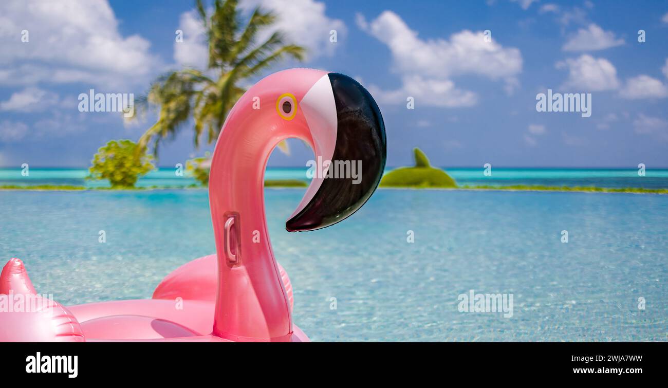 Summer tourism swimming pool inflatable pink flamingo, luxury resort hotel poolside. Happy cloudy sky, tropical paradise island infinity pool sea view Stock Photo