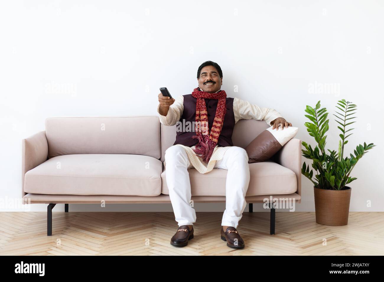 Happy mature indian man watching TV in living room Stock Photo