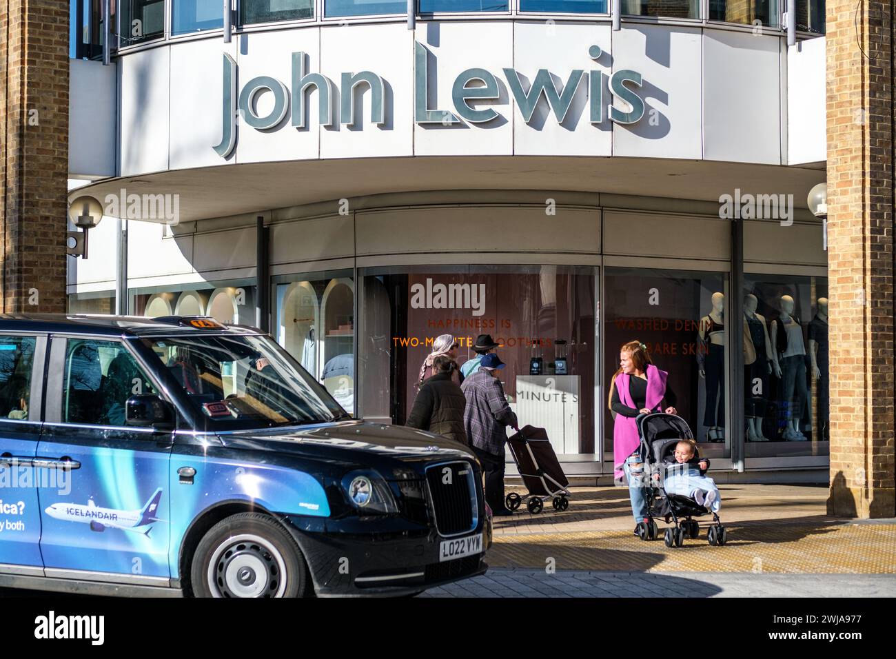 Kingston-Upon-Thames, London UK, February 12 2024, Taxi Passing Outside John Lewis Store With Pedestrians or Shoppers Stock Photo