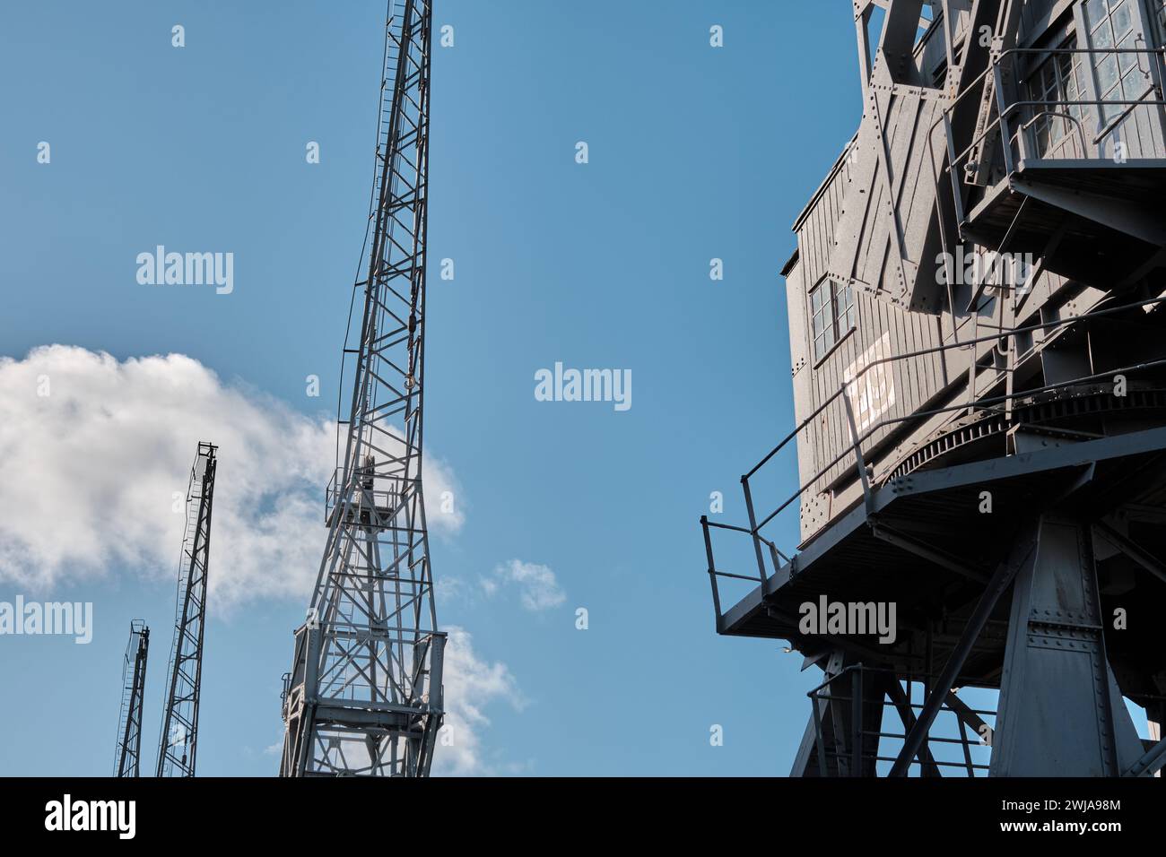 Old disused dockyard cranes on Princes Wharf, Spike Island, Bristol docks, against a blue sky Stock Photo