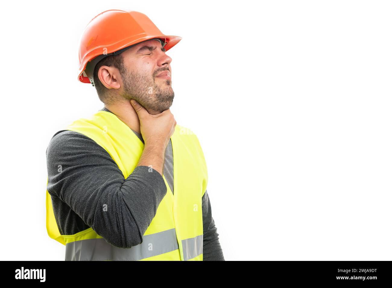 Sick builder man touching neck having sore throat cold flu symptom wearing safety helmet and work vest with blank copyspace isolated on white backgrou Stock Photo