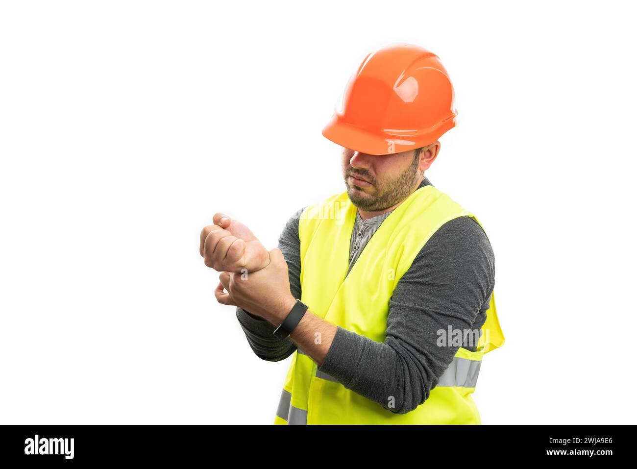 Adult male constructor wearing orange helmet and yellow vest touching painful strained wrist with blank copyspace isolated on white background Stock Photo