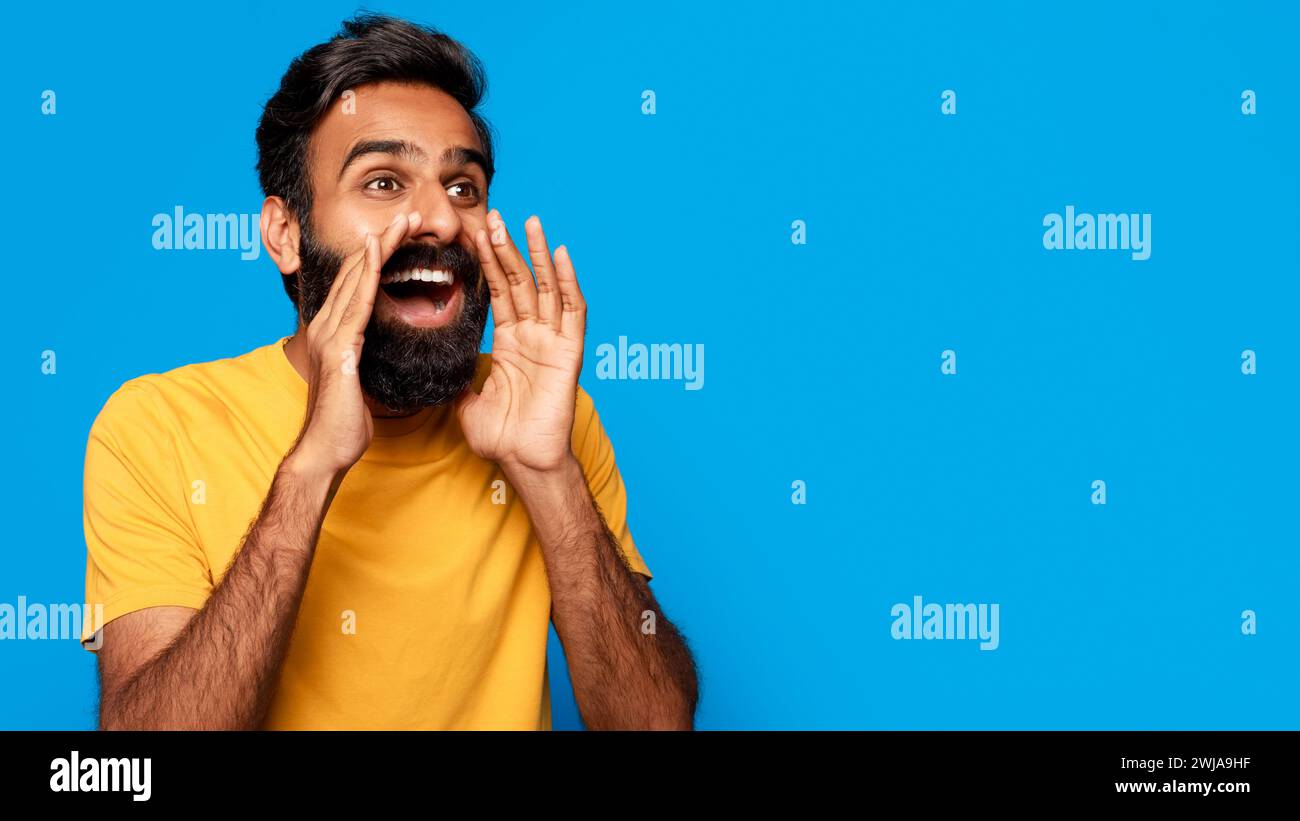 Middle aged indian man shouting message with hands around mouth Stock Photo