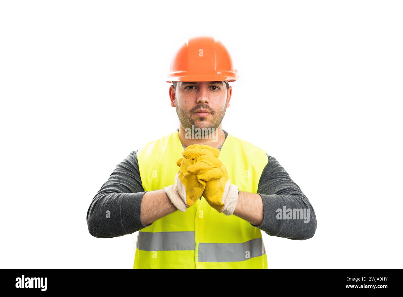 Serious expression male builder wearing trades industry work safety equipment orange helmet and fluorescent vest with yellow gloves isolated on white Stock Photo