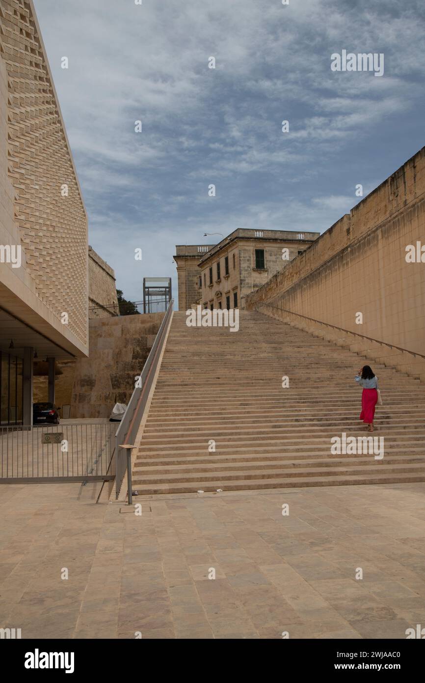A woman ascending steps near a large building  in La Valletta, Malta Stock Photo