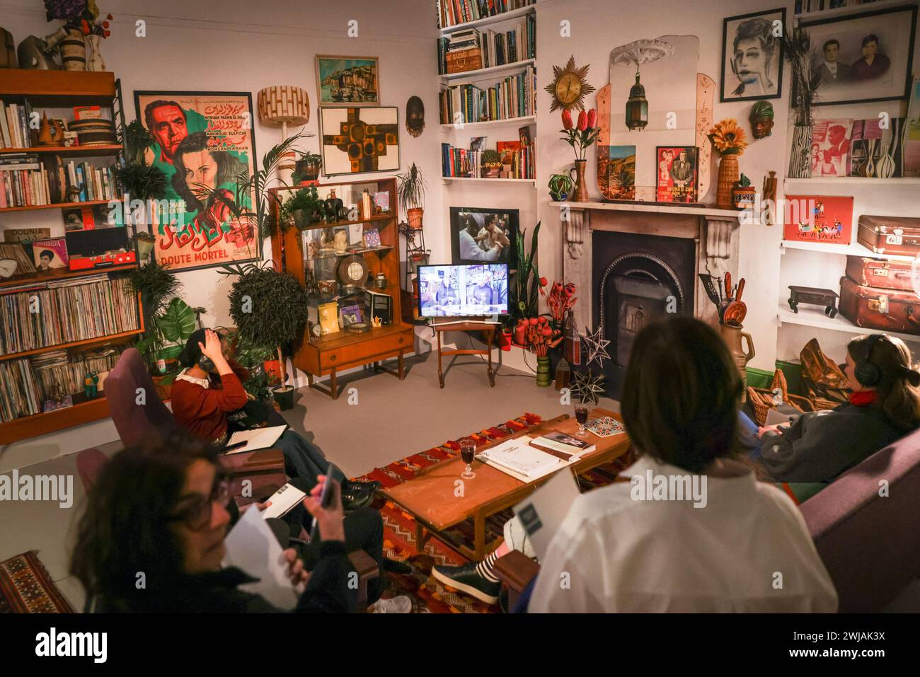 London, UK. 14th Feb, 2024. Staff and visitors in 'Way of Life', 2019 Diorama of the artist living room in Brixton with video. Whitechapel Gallery presents the UK premiere of the acclaimed exhibition ‘Dreams Have No Titles' by French-Algerian artist Zineb Sedira. Encompassing performance, music, dance, installation and film, the exhibition unfolds as a series of immersive sets, exploring avant-garde filmmaking from Algeria, France and Italy during the 60s and 70s. It runs until 12th May. Credit: Imageplotter/Alamy Live News Stock Photo