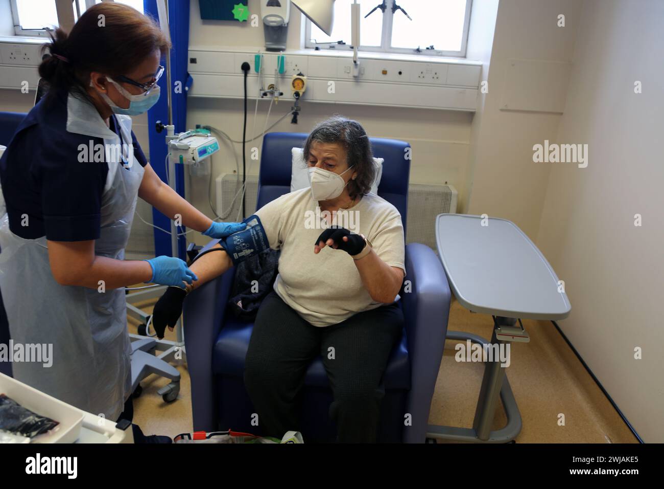 Nurse Using Blood Pressure Cuff on Patient before Administering an Iron Infusion At Hospital Surrey England Stock Photo