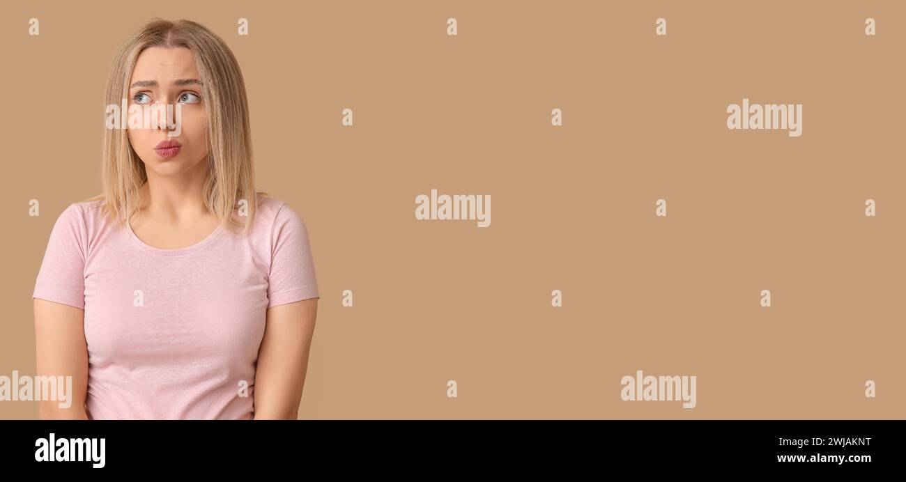 Embarrassed young woman on beige background with space for text Stock ...