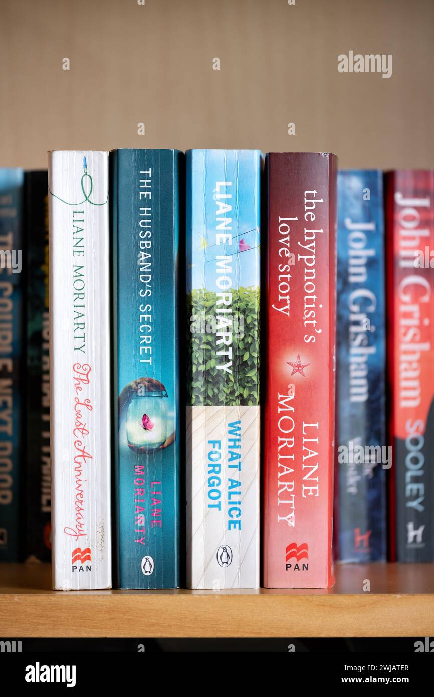 A collection of paperback books or novels on a domestic bookshelf by renown popular Australian author Liane Moriarty. Stock Photo