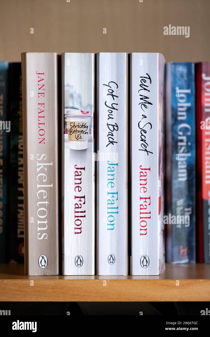 A collection of paperback books or novels on a domestic bookshelf by renown popular English female author Jane Fallon. Stock Photo