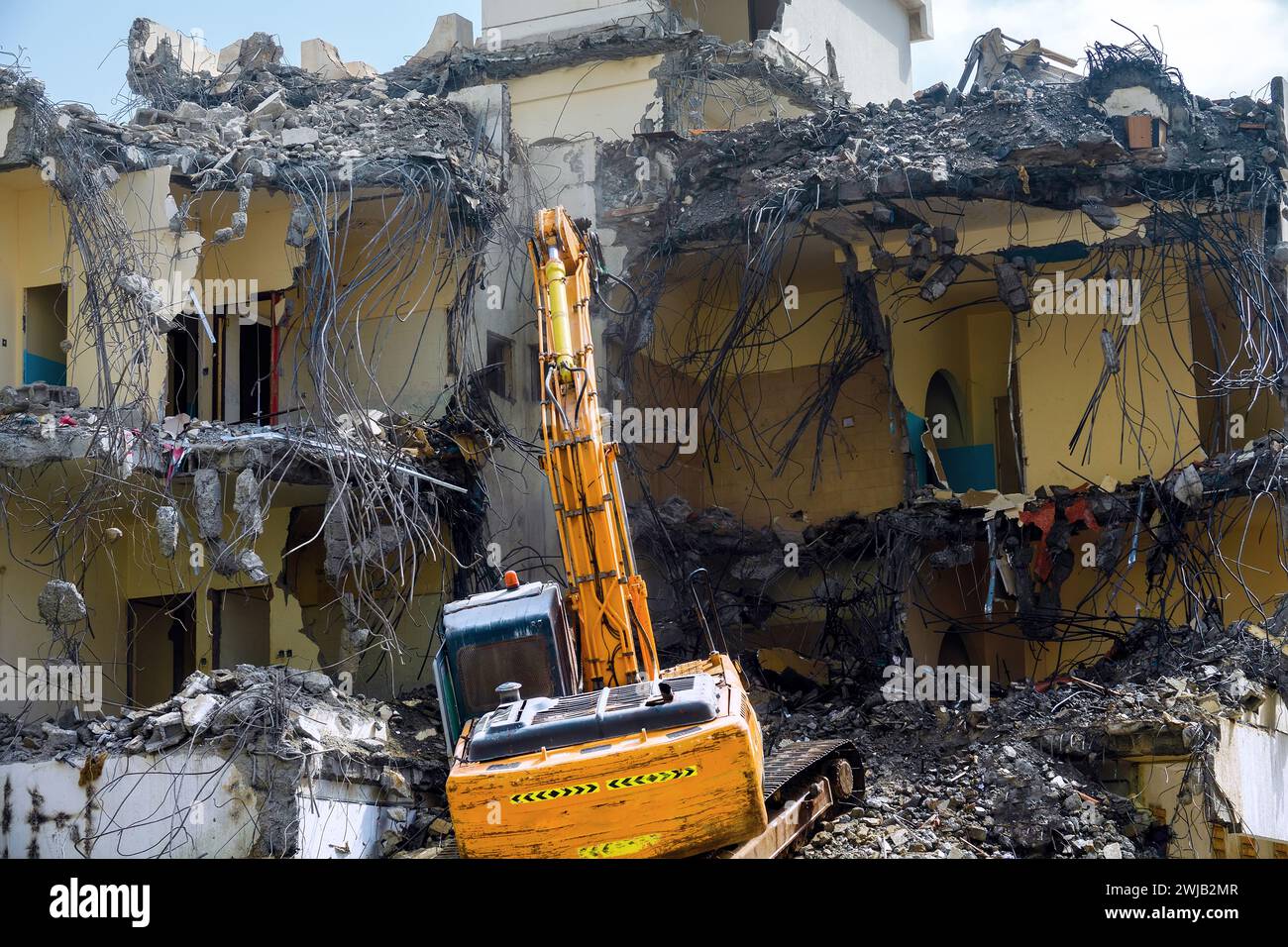 An special excavator destroys an old concrete house. Lots of twisted rebar sticking out, renovation programm Stock Photo