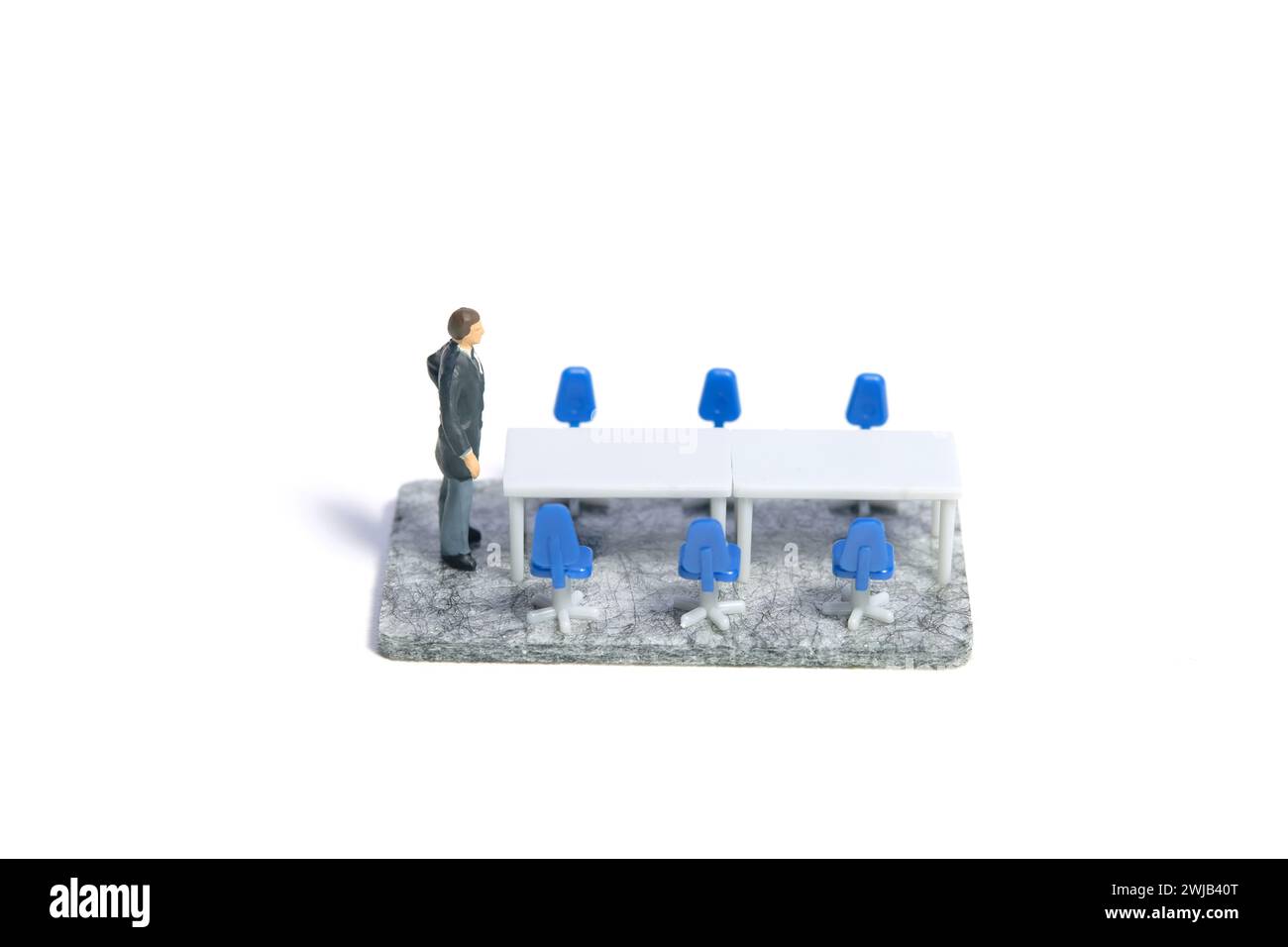 Miniature tiny people toy figure photography. A businessman standing alone on empty meeting room. Isolated on a white background. Image photo Stock Photo