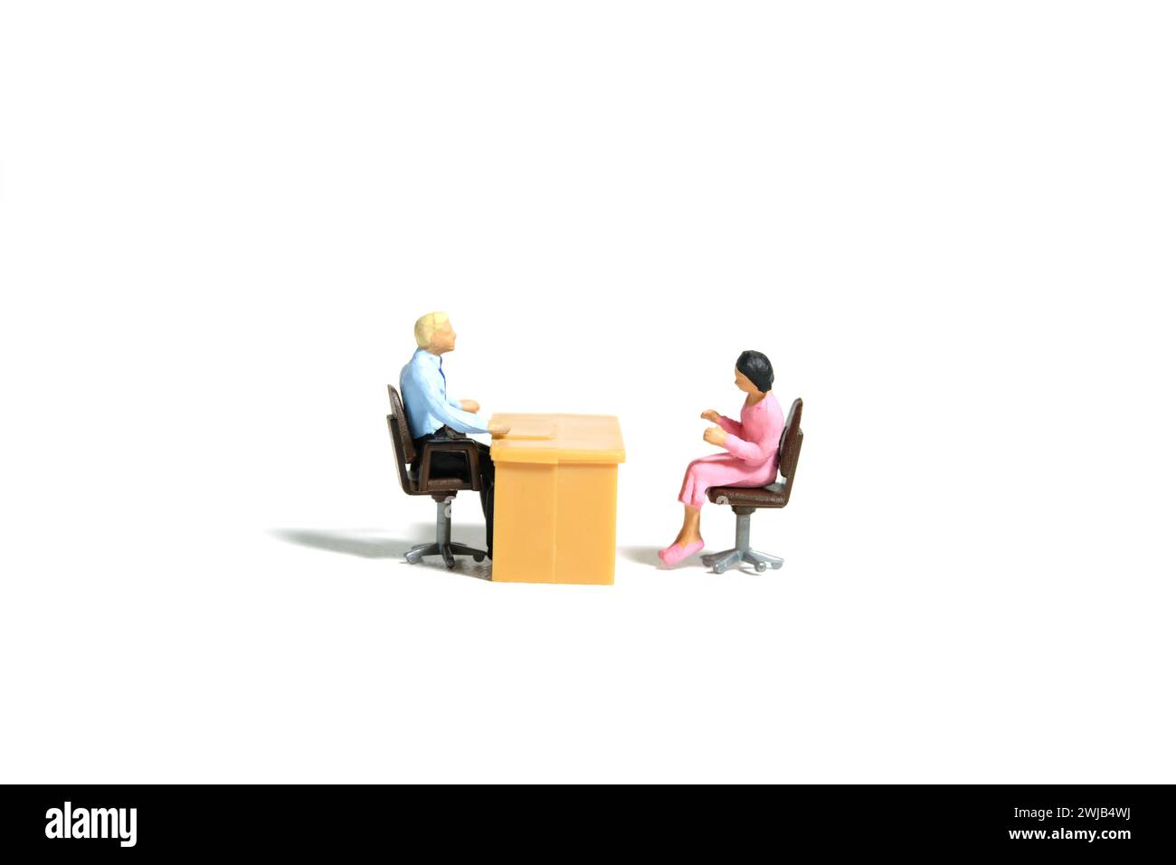 Miniature tiny people toy figure photography. Business conversation concept. A businessman and businesswoman sitting on a chair at office room. Isolat Stock Photo