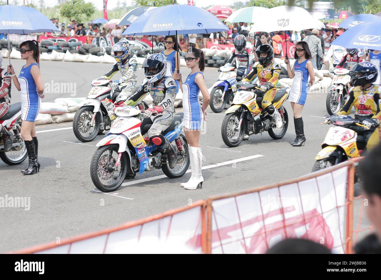 Underbone motorbike racers with asian umbrella girls on start line motor sport racing circuit in Kediri, East Java, Indonesia Stock Photo