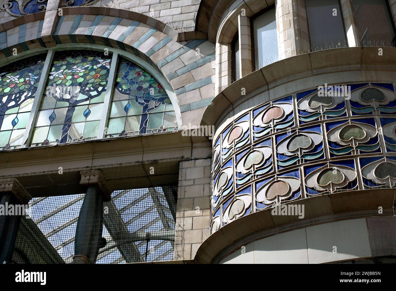 Close up of ceramic tiles above a bowed shopfront window at the east entrance to the Royal Arcade, Norwich. Semicircular stained glass window to left. Stock Photo