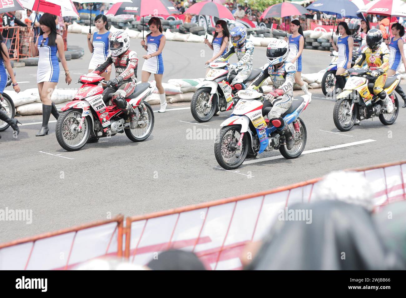 Underbone motorbike racers with asian umbrella girls on start line motor sport racing circuit in Kediri, East Java, Indonesia Stock Photo