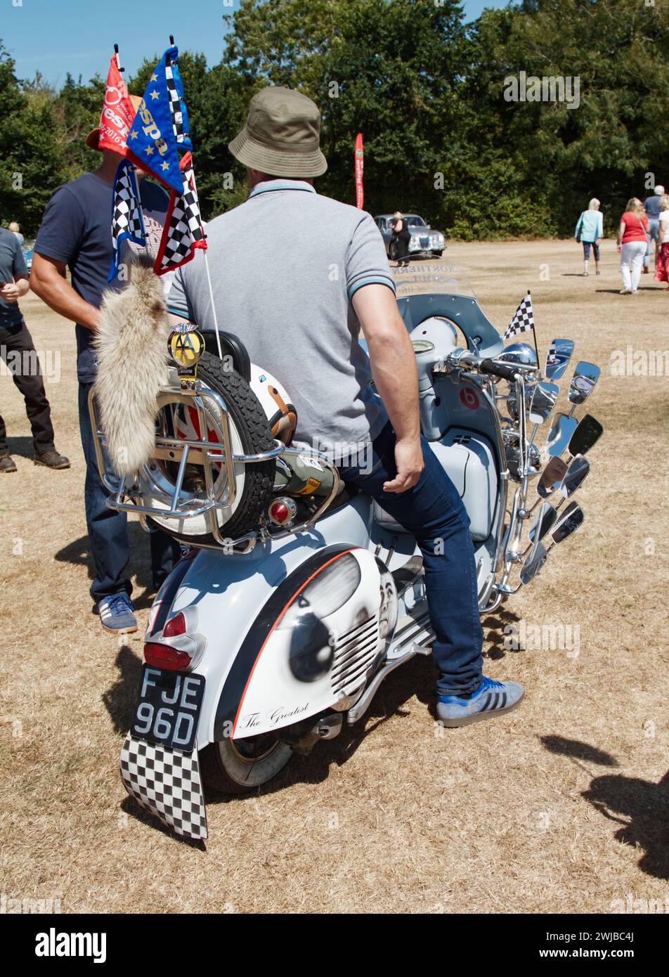 Man In Bucket Hat Sitting On A 1966 Vespa Douglas 124cc Scooter Motorcycle Adorned With Fox Tail, Mirrors, Flags in The Mod Style, Uk Stock Photo