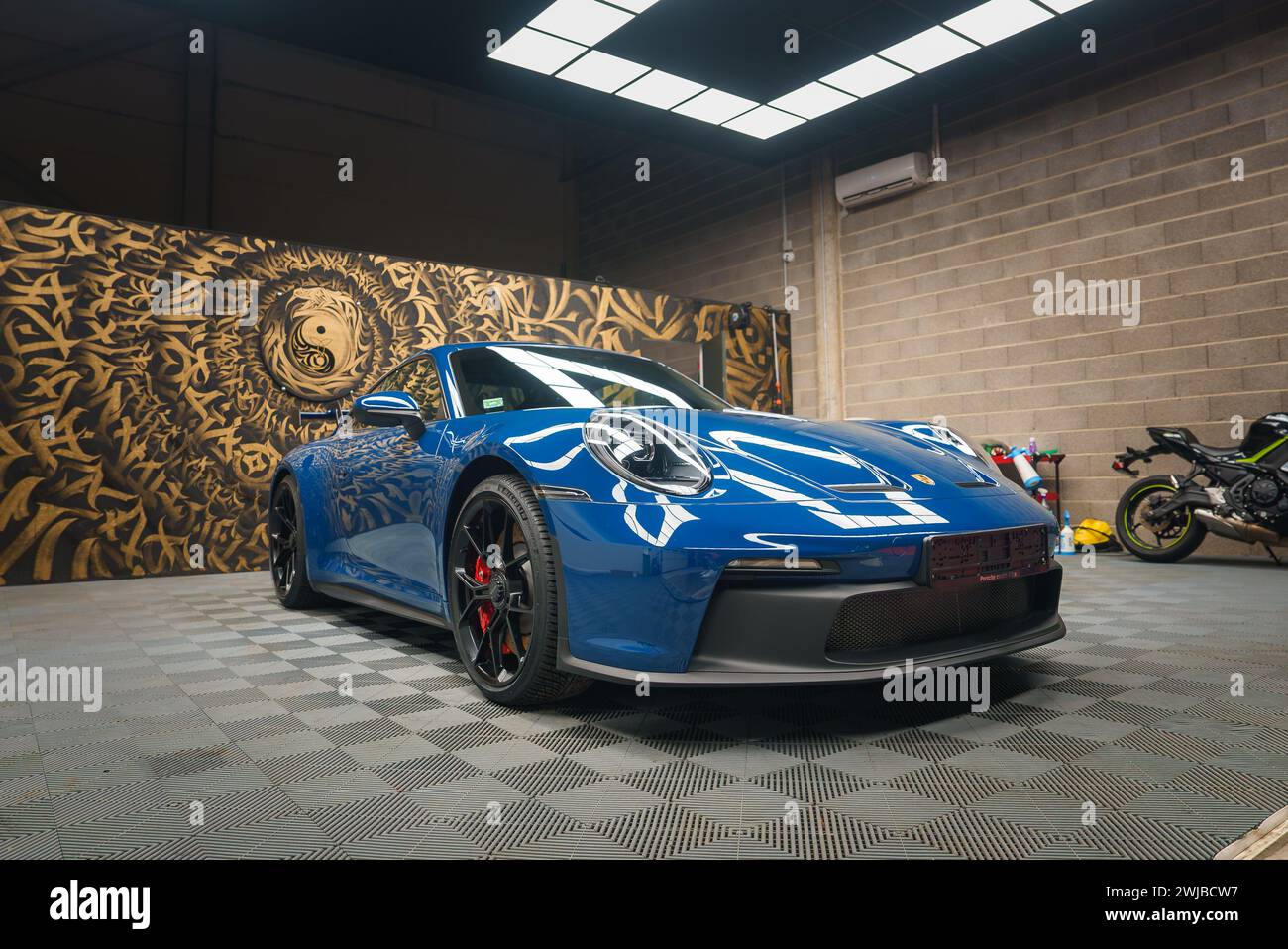 Blue Porsche 911 GT3 with Artistic Mural Backdrop in Modern Garage Stock Photo